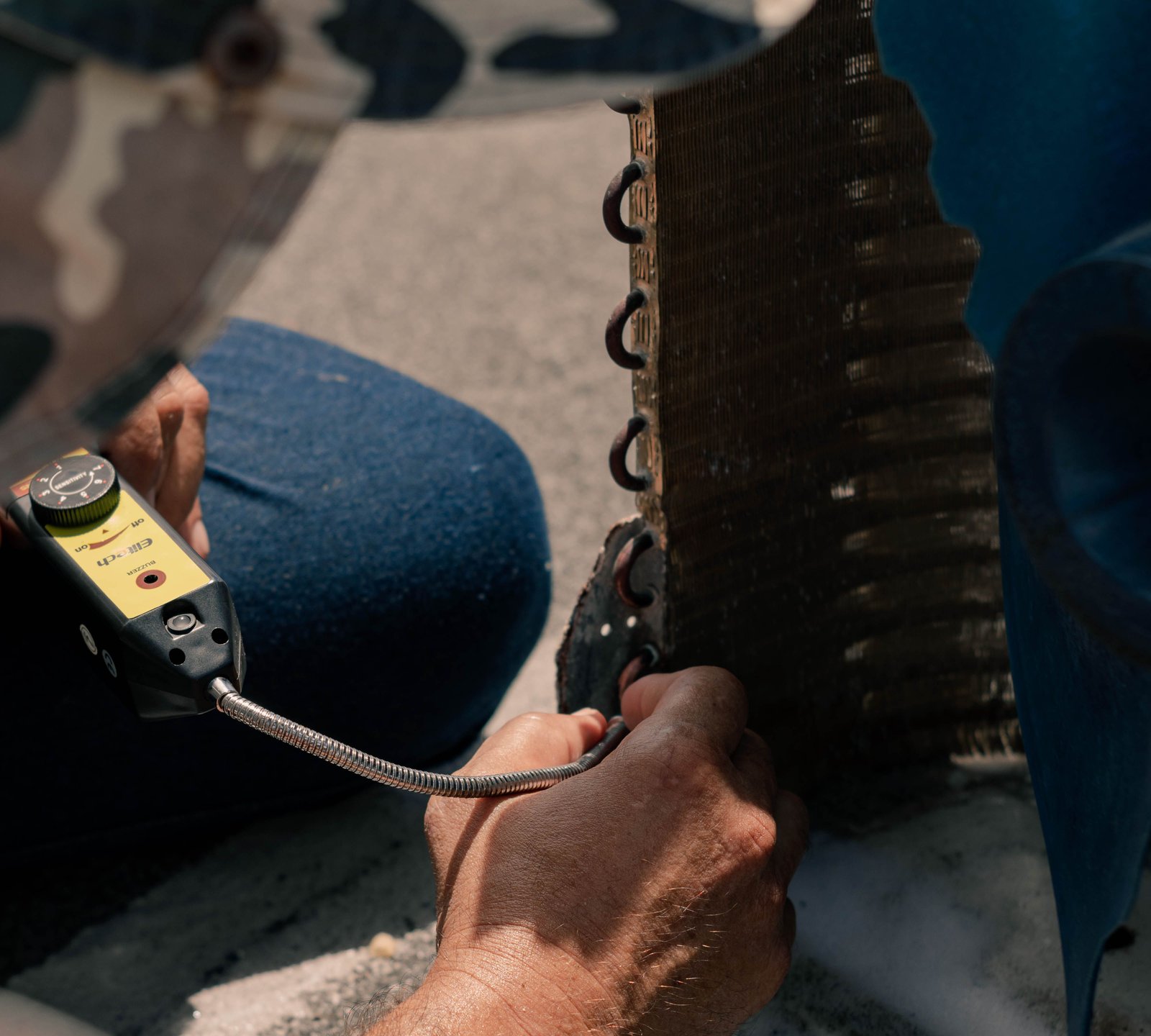 Technician using a leak detector on the coil of an outdoor air conditioner
