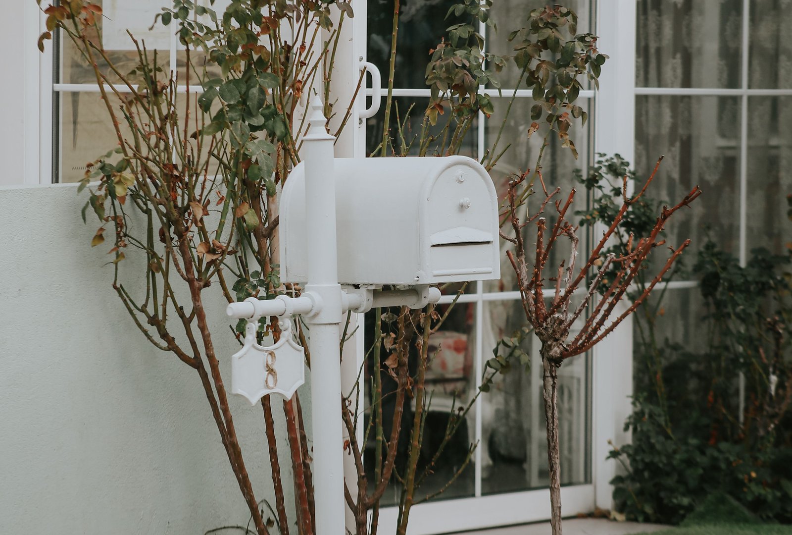 White curbside-style mailbox on a post in front of a home
