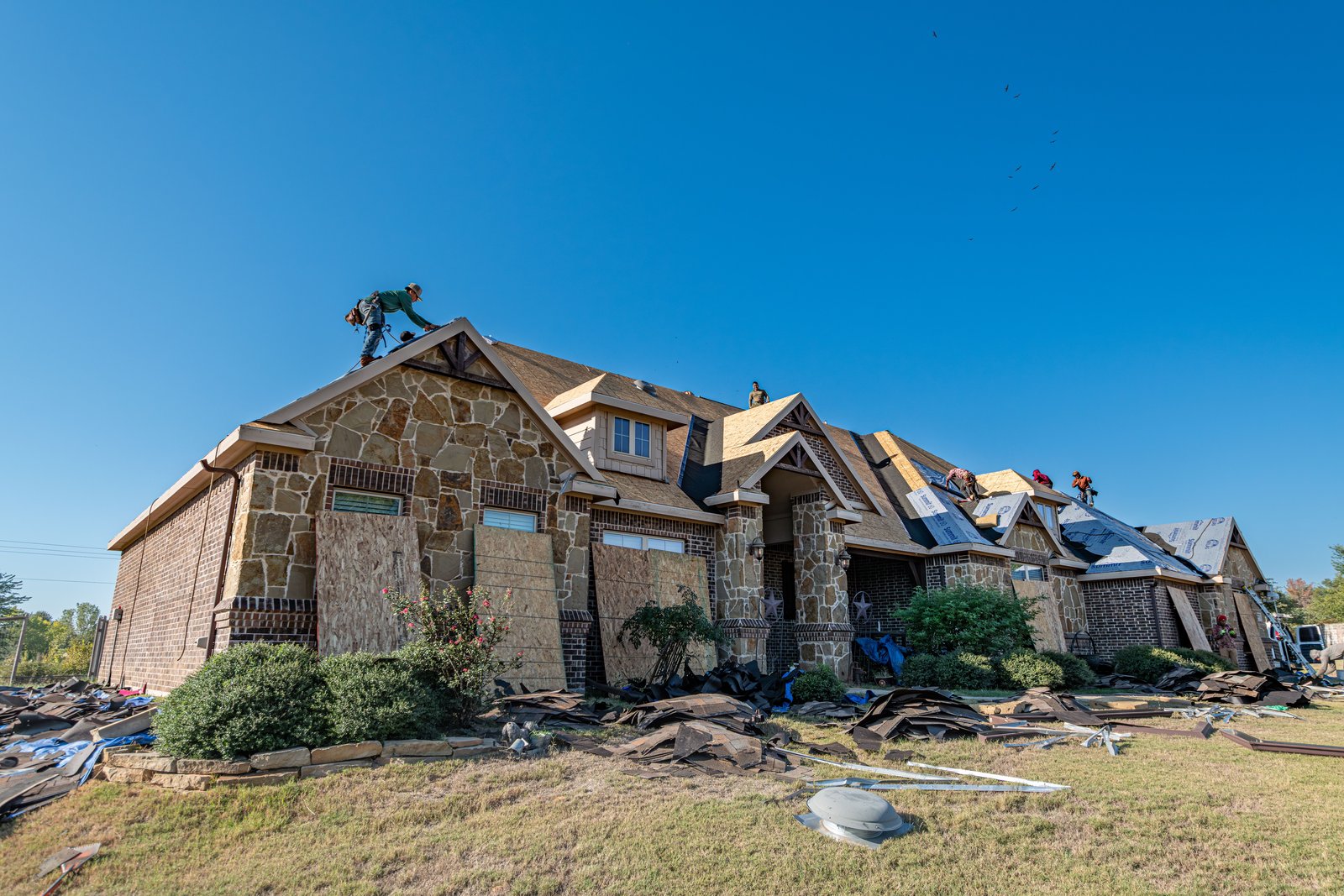 Roofing crew installing a new roof on a brick house in Texas
