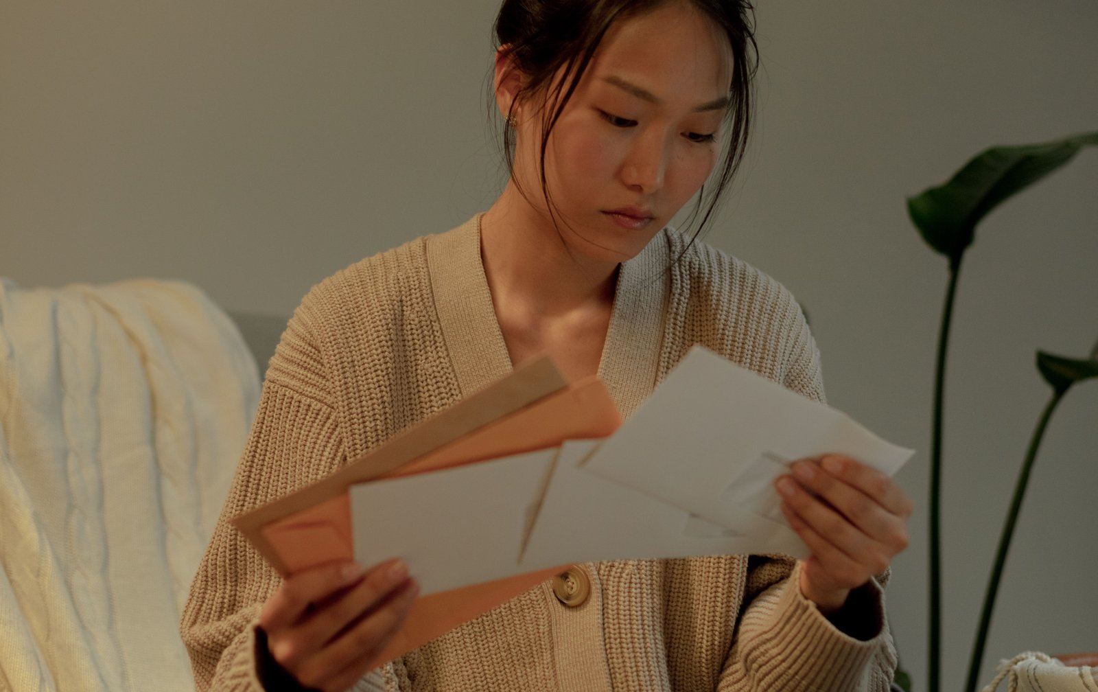 Woman sitting on a sofa reading letters from her mail